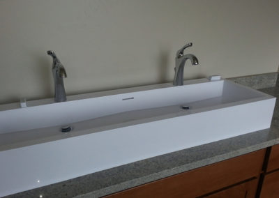 Long bathroom sink with two chrome faucets installed by Ken Paulson Plumbing
